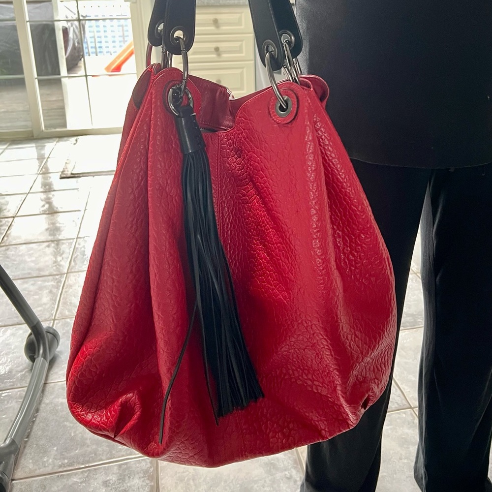 Beautiful red tote pocketbook with black straps and black fringes.